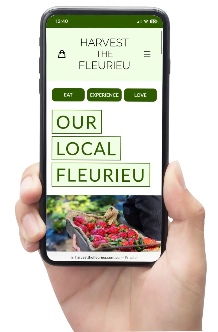 Hand holding phone with Harvest the Fleurieu website on screen