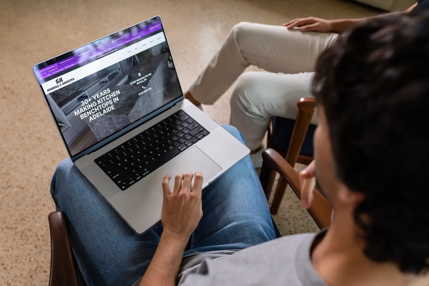 Sav holding a laptop showing SA Marble and Granite website