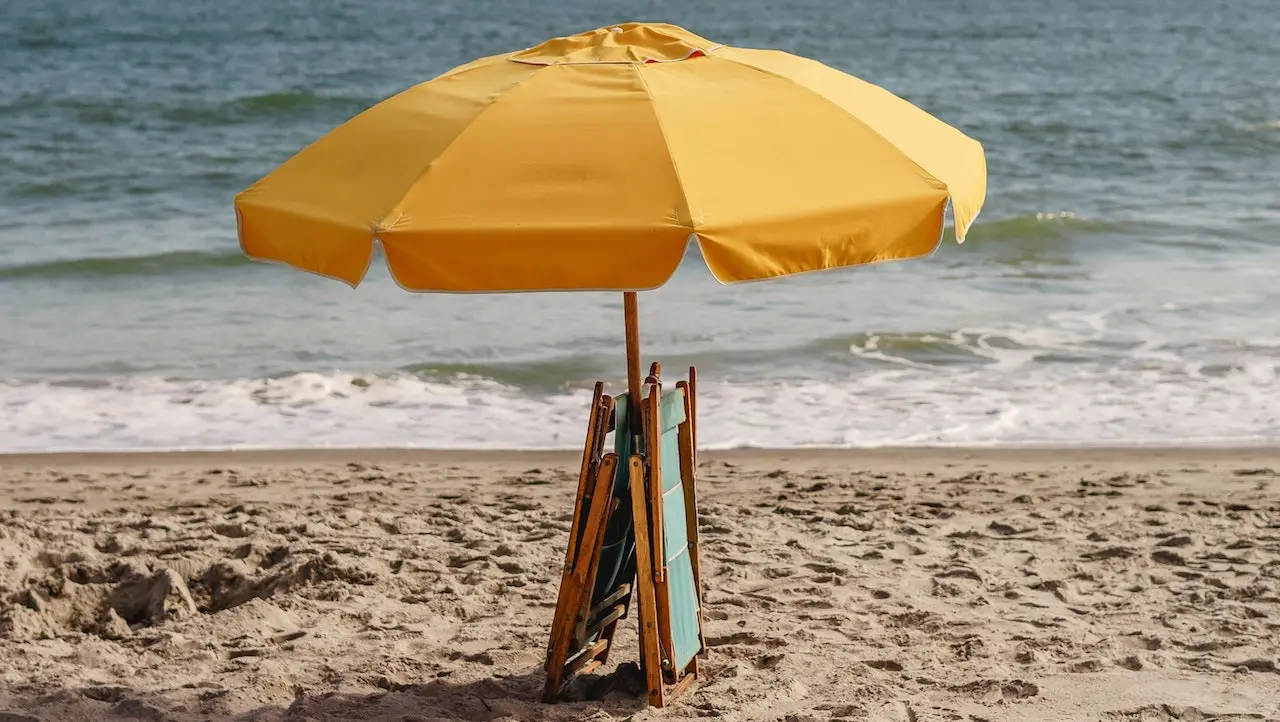 An image of an yellow umbrella on a beach.